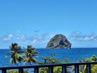 a view of a rock in the ocean with palm trees at Studio A101, près de la mer Village du Diamant in Le Diamant