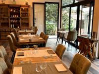 ein Restaurant mit Holztischen und -stühlen und Fenstern in der Unterkunft Le Clos des Arbousiers in Linguizzetta