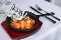 Una sartén con camarones y verduras sobre una mesa. en Hotel casona de los ríos, en Futrono