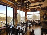 Un comedor con mesas y sillas y grandes ventanales. en Hotel Riverside Inn, en Martuni