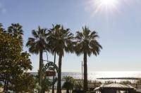 Una vista de la playa desde un resort con palmeras. en Hotel Kristina, en Imperia