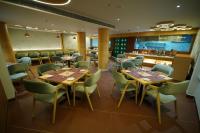 a restaurant with wooden tables and green chairs at Regenta Inn Bhavani Nellore By Royal Orchid Hotels in Nellore