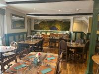 ein Restaurant mit Tischen und Stühlen und einem Gemälde an der Wand in der Unterkunft The Castle Coaching Inn in Trecastle