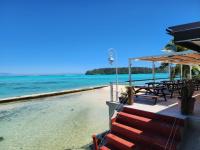 a beach with tables and chairs and the ocean at Hotel Hibiscus in Papetoai