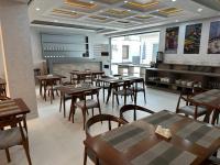 Un restaurante con mesas y sillas de madera en una sala. en Ohu Palace, en Ferganá
