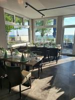 una sala da pranzo con tavoli, sedie e finestre di Strandappartement Steinberghaff "zur Birk" mit Meerblick a Steinberg