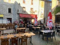 een buitenrestaurant met tafels, stoelen en parasols bij Café du Commerce in Génolhac