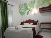 1 dormitorio con 1 cama con sábanas blancas y cortinas verdes en Goalma Family Holiday Resort &amp; Restaurant, en Anuradhapura