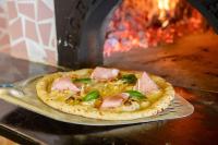a pizza sitting on a pan in front of an oven at Los Felices Ibiza in San Antonio Bay