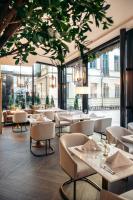 um restaurante com mesas e cadeiras brancas e grandes janelas em Waldorf Astoria Helsinki em Helsínquia