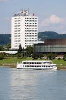 a white boat on the water in front of a building at ARCOTEL Nike Linz in Linz