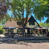 ein Gebäude mit Tischen und Sonnenschirmen und einem Baum in der Unterkunft B&B Hartje Exloo in Exloo