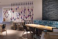 Un restaurante con mesas y sillas y una pared con flores en Renaissance Newport Beach Hotel, en Newport Beach