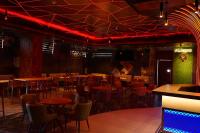 uma sala de jantar com mesas, cadeiras e iluminação vermelha em raj Regent kurichy em Putuppalli