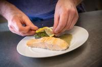 a person is cutting a piece of fish on a plate at Oh Activ Cergy in Cergy