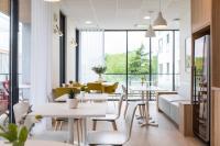 a restaurant with tables and chairs and windows at Oh Activ Cergy in Cergy