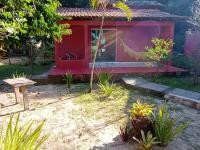 a red house with a hammock in front of it at Pousada ZEN Cumuruxatiba in Cumuruxatiba