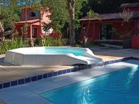 a swimming pool with a tub next to a house at Pousada ZEN Cumuruxatiba in Cumuruxatiba