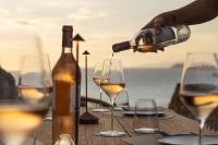 una persona sirviendo vino en copas sobre una mesa en Yfes, en Kithnos