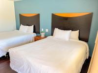 zwei Betten in einem Hotelzimmer mit weißen Laken in der Unterkunft Town and Country Inn in Santa Barbara