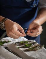 una persona cortando pescado encima de una mesa en Bethlen Estates Transylvania, en Daneş