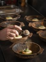 Una persona está sirviendo comida en tazones sobre una mesa. en Bethlen Estates Transylvania, en Daneş