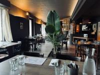 a restaurant with tables and chairs and a plant at Logis Hotel Eben in Égletons