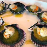 Un plato de ostras en un plato con salsa. en Hotel Rural y Restaurante, Rinconcito de Gredos, en Cuevas del Valle