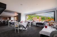 サン・ディエにあるLogis Hôtel Le Régal & Spaのテーブルと椅子と大きな窓のあるレストラン