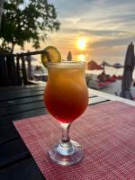 ein Getränk im Glas auf einem Tisch mit Sonnenuntergang in der Unterkunft Amara Beach Resort Koh Phangan in Haad Yao