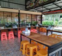 een restaurant met houten tafels en gele stoelen bij Khumkatang Resort & Restaurant in Ban Bang Rong