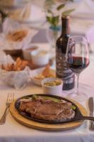 un plato de carne en una mesa con una copa de vino en Hotel Santa Anita - Balderrama Hotel Collection, en Los Mochis