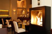 Un restaurante con mesas y sillas y una chimenea. en Inselhotel König, en Norderney