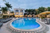 a pool with chairs and umbrellas in front of a hotel at NH Haiti El Rancho in Port-au-Prince