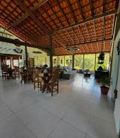 un ampio soggiorno con soffitto in legno, tavoli e sedie di Chalé Estância do Coruja a Salesópolis