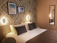 a bed in a hotel room with two pictures on the wall at Rinascitel Larmor Plage in Larmor-Plage