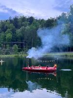 ein rotes Boot auf einem See mit einem Schornstein in der Unterkunft Creekside Modern Tiny Home - Firepit - Racoon Cabin in Gatlinburg
