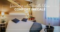 a bedroom with a white bed with blue pillows at Hôtel Inn Design - Restaurant L&#39;Escale in Rochefort