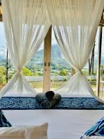 two beds in a room with white curtains at The volcano in Kubupenlokan