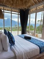 a bed with blue and white pillows in a room with windows at The volcano in Kubupenlokan