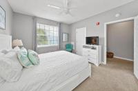 ein weißes Schlafzimmer mit einem Bett und einem Fernseher in der Unterkunft Sunny escape in Miramar Beach in Destin
