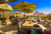 un restaurante con mesas y sillas con pirámides en el fondo en Onyx Pyramids Boutique Hotel, en El Cairo