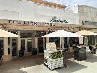 un hombre sentado en una mesa frente a un hotel en The Link Hotel South Beach, en Miami Beach