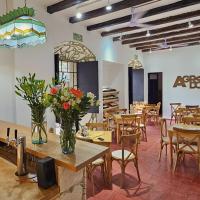 een restaurant met tafels en stoelen en een vaas met bloemen bij Agrado Guest House in Oaxaca City