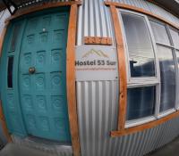 un edificio con dos puertas y una señal en él en Hostel 53 Sur, en Puerto Natales