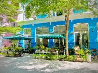 富国Laputa Hotel Phú Quốc的蓝色的建筑,前面设有桌子和遮阳伞