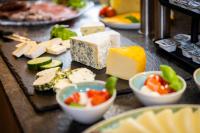 Una mesa con diferentes tipos de quesos y verduras. en Winklers Gipfelblick Chalet, inklusive Alpentherme - Ganzjährig, Gasteiner Bergbahn - nur Sommer, en Bad Hofgastein