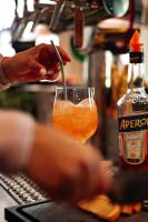 una persona revolviendo una bebida en un vaso al lado de una botella en Landgasthof-Unter den Linden, en Oelixdorf