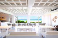 una sala da pranzo con tavoli e sedie bianchi e l'oceano di Pricia Resort Yoron a Yoron