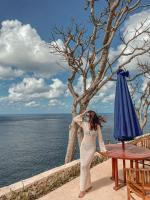 una donna in piedi accanto a un tavolo con un ombrello di Aloka Penida a Klungkung